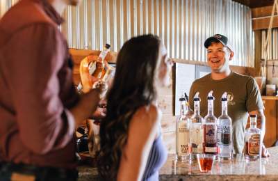 Picture of a couple enjoying drinks while speaking to the owner of the distillery they are at, at Balance Distilling Company
