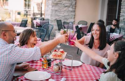 Family of 4 cheers drinks while dining at Grimaldi's on the patio.