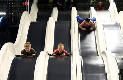 Slick City 3 kids sliding down white slides parallel.