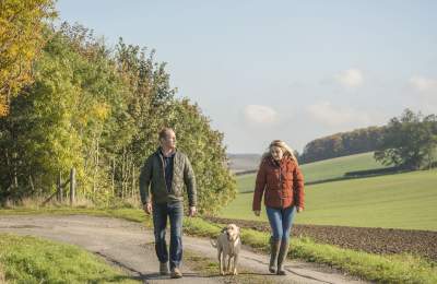 Couple walking a dog at Sledmere House in Winter