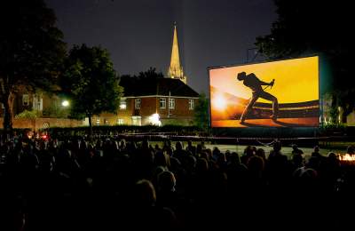 A picture showing an outdoor cinema screen with an audience