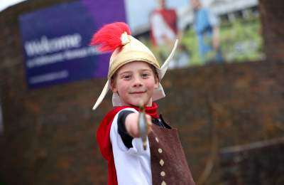 A child wearing a Roman helmet and sword at Fishbourne roman palace