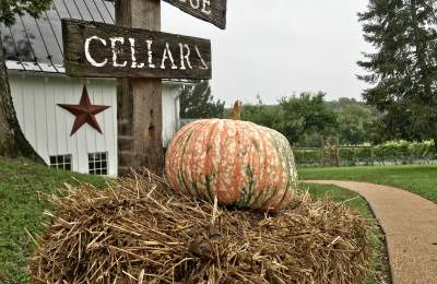 Heirloom pumpkin on a hay bale beside the rustic Cellars sign at Barns at Hamilton Station in Hamilton, Virginia