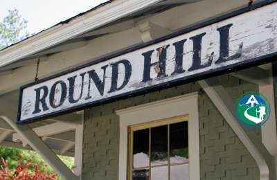 Weathered Round Hill sign on the historic train station, with the Appalachian Trail Community designation badge