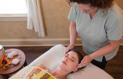 Masseuse rubbing woman's temples at spa