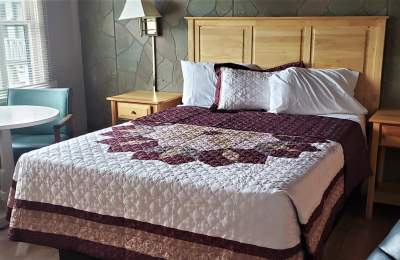Large bed with light-wood headboard and quilt