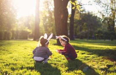 Two girls with bunny headbands on searching for easter eggs in a field