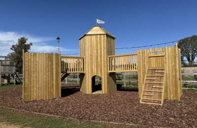 A wooden outdoor castle themed climbing frame