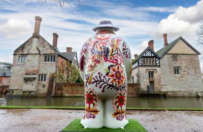 The rear view of a painted snowman statue facing the moat and Baddesley Clinton