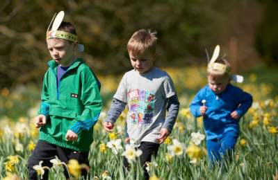 Children wearing easter bunny ears walking through a wildflower meadow on a sunny day at Upton House and Gardens