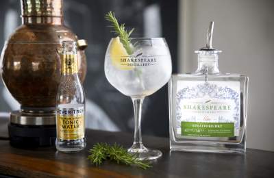 A gin and tonic next to a bottle of Stratford Gin by Shakespeare Distillery with a bottle of Fever Tree Tonic