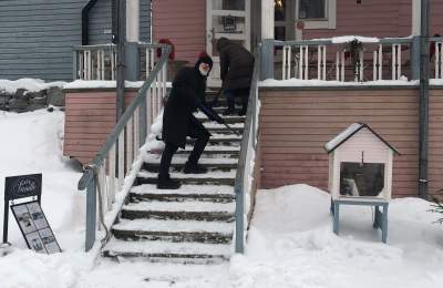 People climbing snow covered steps to enter a cafe in winter.