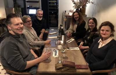 A group of people seated at a table share drinks and get ready to dine.
