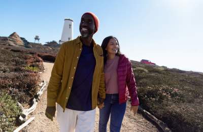 Couple walking along path with Piedras Blancas Light Station in background