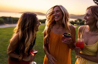 Three women talking and smiling with curled hair at sunset