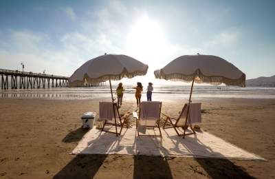 Beach chairs and umbrellas set up on the sand with women running towards the water in the background