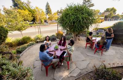 Group of people sitting outside at red tables wine tasting in downtown