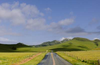 Empty road leading to green hills