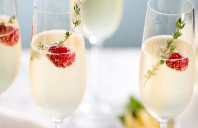 Flutes of sparkling wine with berry and herb garnish