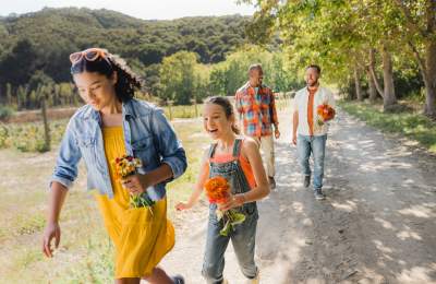 2 kids and 2 adults walking with fresh picked flowers