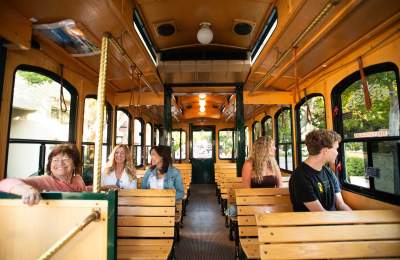 Interior view of five riders on the Old SLO Trolley talking and looking out the window