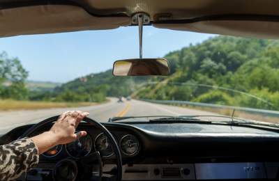 Looking through windshield at road and green hills