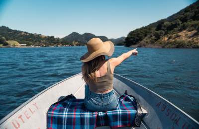 Women wearing sun hat on boat in the middle of a lake pointing at the hill
