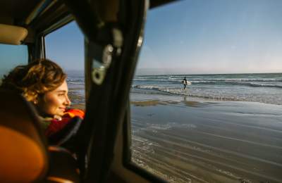 Woman looking out of a car window while driving on the beach