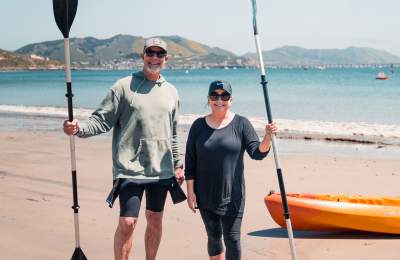 Couple holding kayak oars standing on the beach in Avila Beach