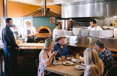 Ember Restaurant Dining Room.  Chefs cooking in background and diners eating in foreground.