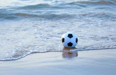 Black and white soccer ball in shallow water on the beach