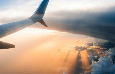Airplane Flying Out of Clouds and Into the Sunset