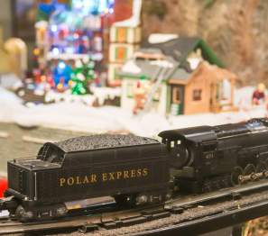 A model train rides through a Christmas Village
