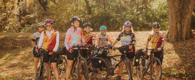 Group of women cyclists posing with their bikes along a tree-lined trail during fall in Mountain Maryland.