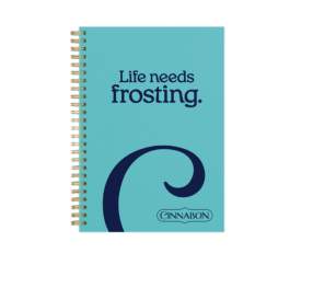 An image of a blue spiral journal branded with Cinnabon that says "Life Needs Frosting"