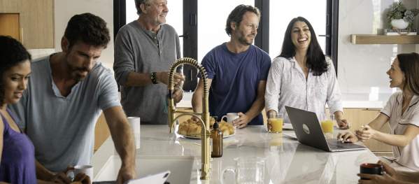 Co-workers sharing croissants for breakfast standing around kitchen island