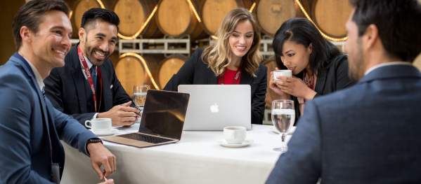 A group of people in business suits holds a meeting inside a winery