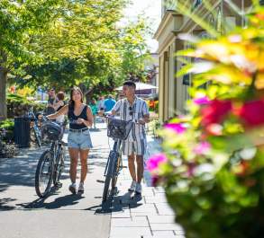 Two cyclists walking their bikes down the main street