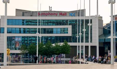The ICC and Symphony Hall building seen across Centenary Square in Birmingham, with people milling about in front of the building.