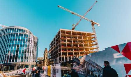 Cranes tower over the development in Paradise, Birmingham, as pedestrians walk below.