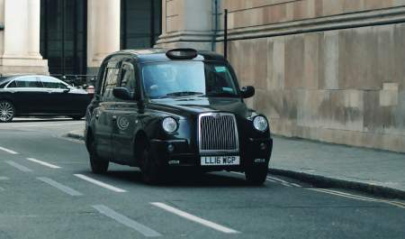 A taxi waiting at the side of the road for a passenger