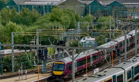 Wide view photograph of train tracks coming into the city, with a West Midlands Railway train on the tracks