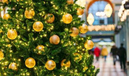A closeup photograph of a Christmas tree with the shops of the Great Western Arcade in the background