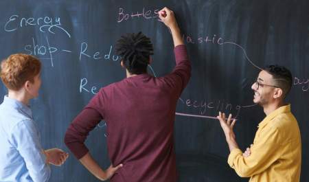 Three people work together to create a plan on a blackboard