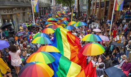 Birdseye view of the crowd carrying rainbow umbrellas and a giant rainbow flag at Birmingham Pride Festival