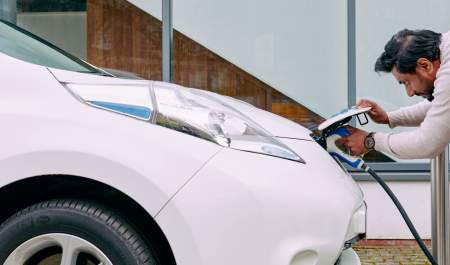 A man plugs in an electric car to charge