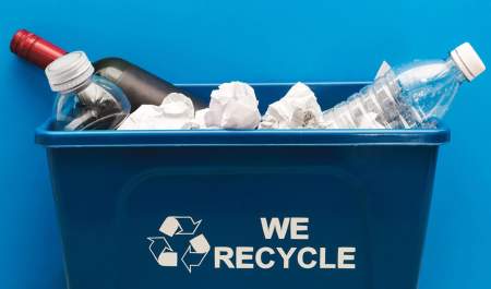 Recycling bin with filled with paper, glass and plastic bottles