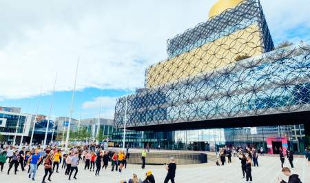 A group of people standing in Centenary Square in front of the Library of Birmingham