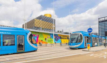 Two blue West Midlands trams outside of Birmingham library