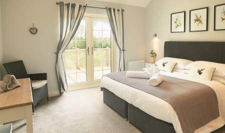 Wakes Hall Lodges room with double bed chair and television